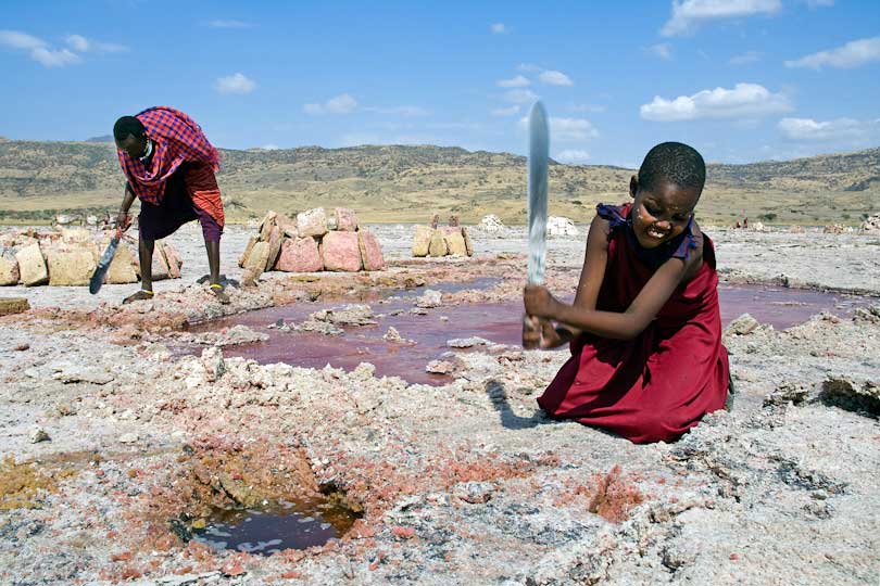 Soda mining, a young Massai girl cuts salt slabs <p>with a machete, Lake Natron, Tanzania,